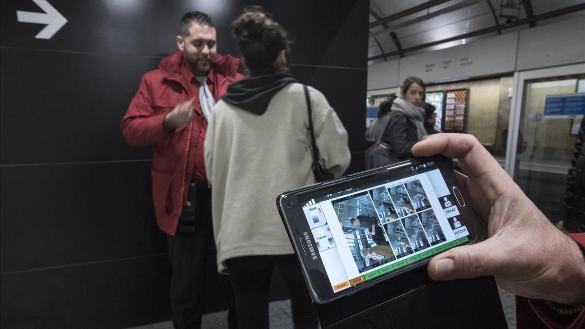 Un interventor pide el billete a Berta, cuya foto colándose se ve en el móvil que sostiene un segundo revisor. Un interventor pide el billete a Berta, cuya foto colándose se ve en el móvil que sostiene un segundo revisor.