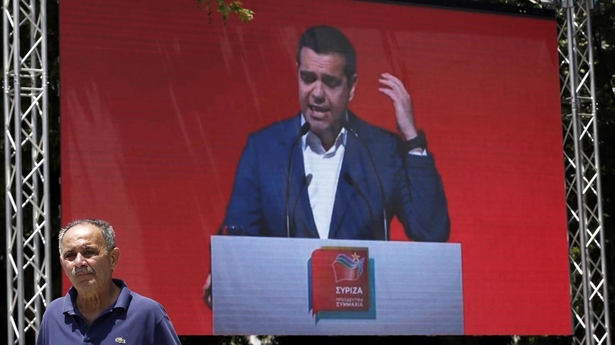Un hombre pasa frente a una pantalla en la que se proyecta un mitin de Tsipras en Atenas, el pasado 18 de mayo. Un hombre pasa frente a una pantalla en la que se proyecta un mitin de Tsipras en Atenas, el pasado 18 de mayo.