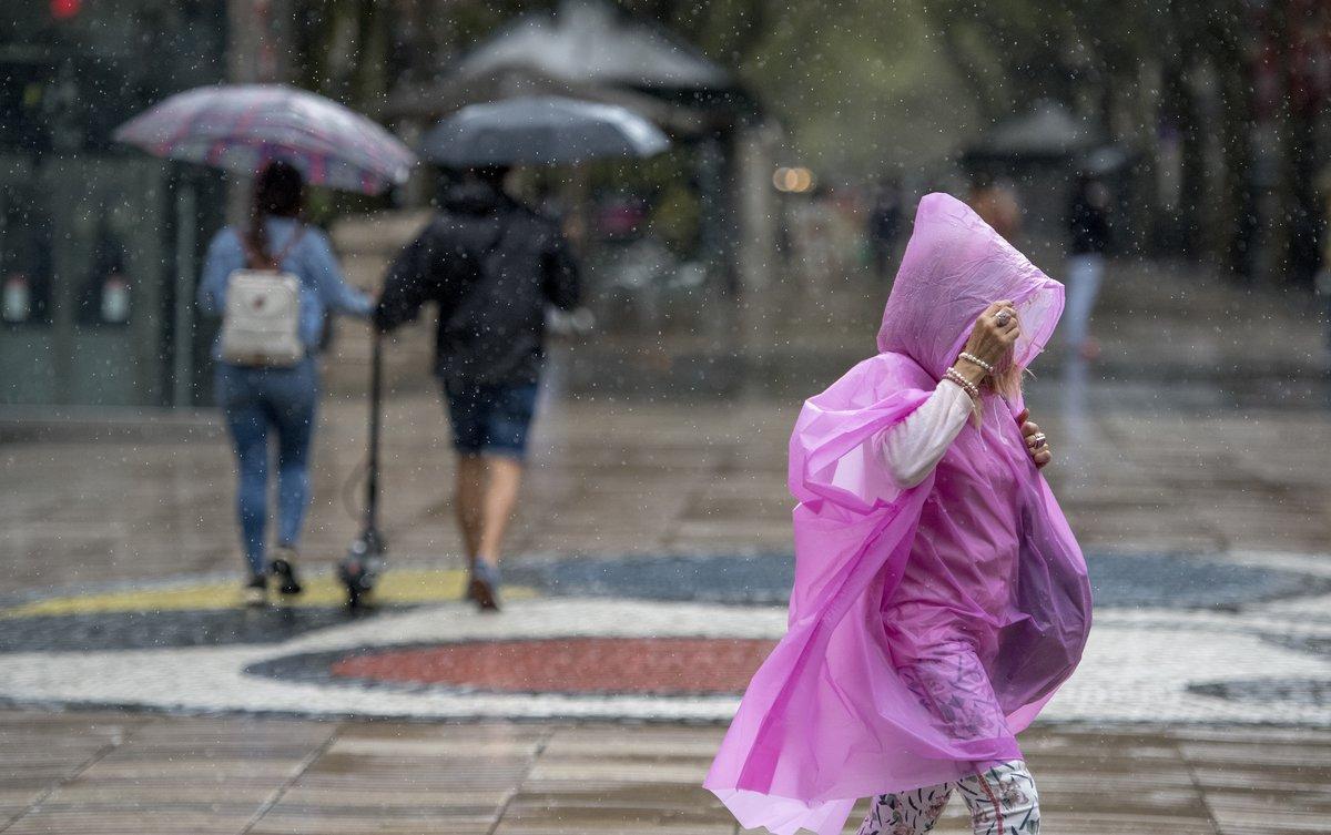 Varias personas se protegen de la lluvia, en las Ramblas de Barcelona.