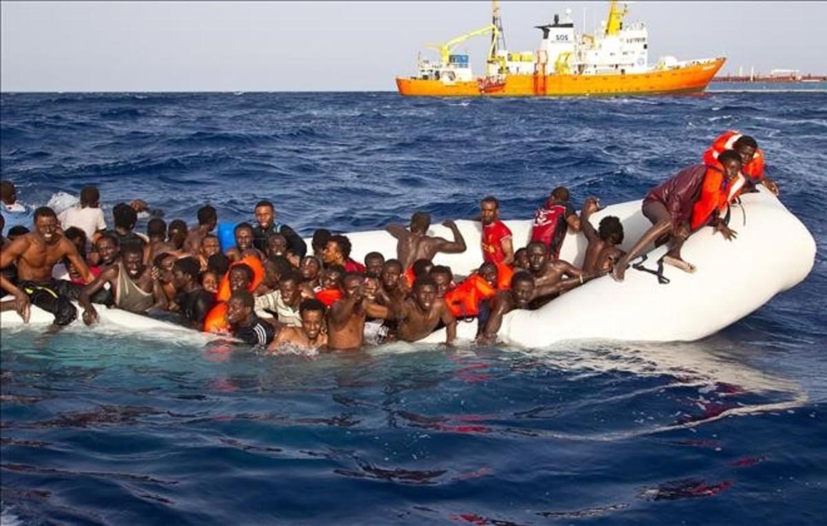 Momento en que varios inmigrantes son rescatados el lunes en alta mar cerca de la costa italiana.