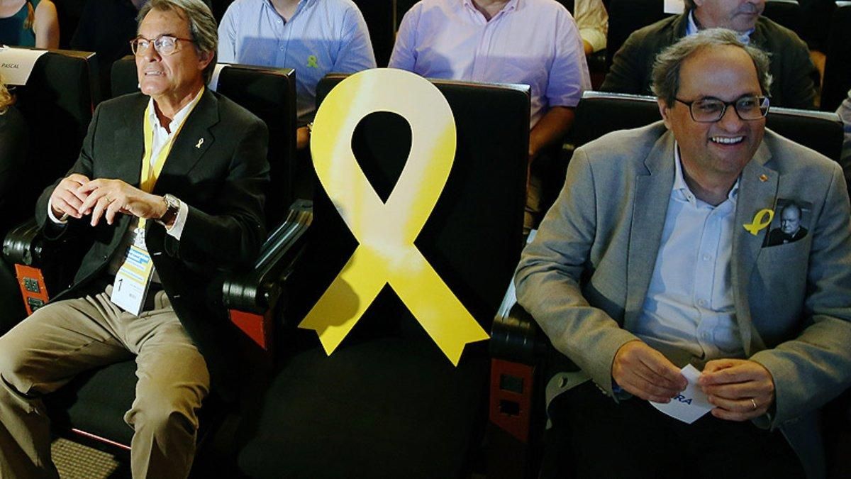 Artur Mas y Quim Torra flanquean un lazo amarillo en representación de Carles Puigdemont en un acto del PDECat. Artur Mas y Quim Torra flanquean un lazo amarillo en representación de Carles Puigdemont en un acto del PDECat.