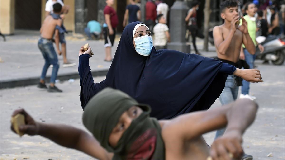 Unos jóvenes lanzan piedras a la policía en una de las protestas de esta semana en Beirut.