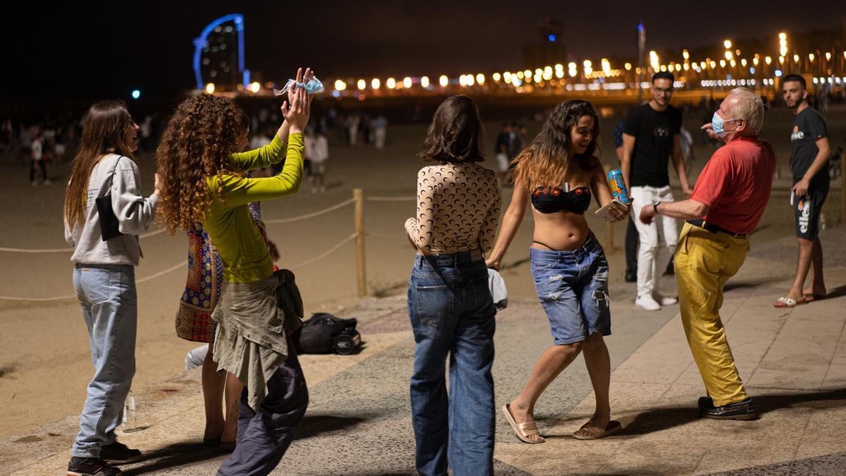 Un grupo de chicas y un señor bailan a pie de playa en la Barceloneta