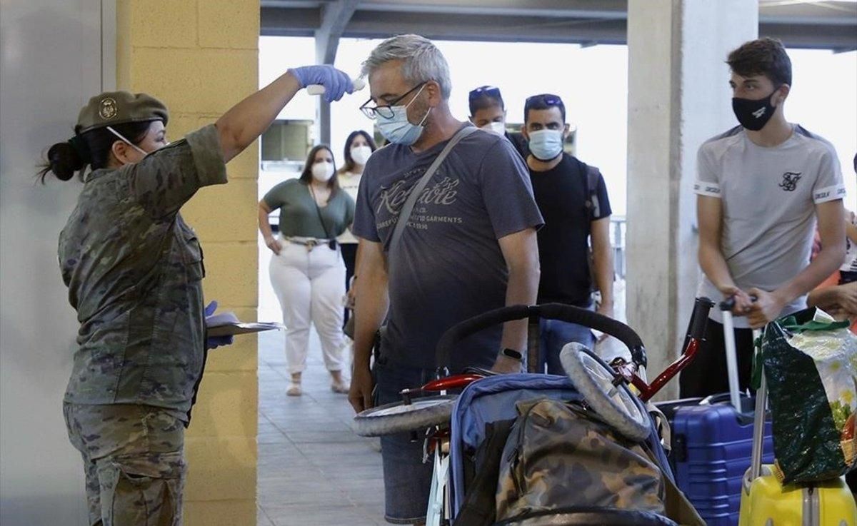 Una enfermera del Ejército toma la temperatura a los pasajeros del barco procedente de Málaga durante un control sanitario a su llegada a Melilla, el 19 de junio. Una enfermera del Ejército toma la temperatura a los pasajeros del barco procedente de Málaga durante un control sanitario a su llegada a Melilla, el 19 de junio.