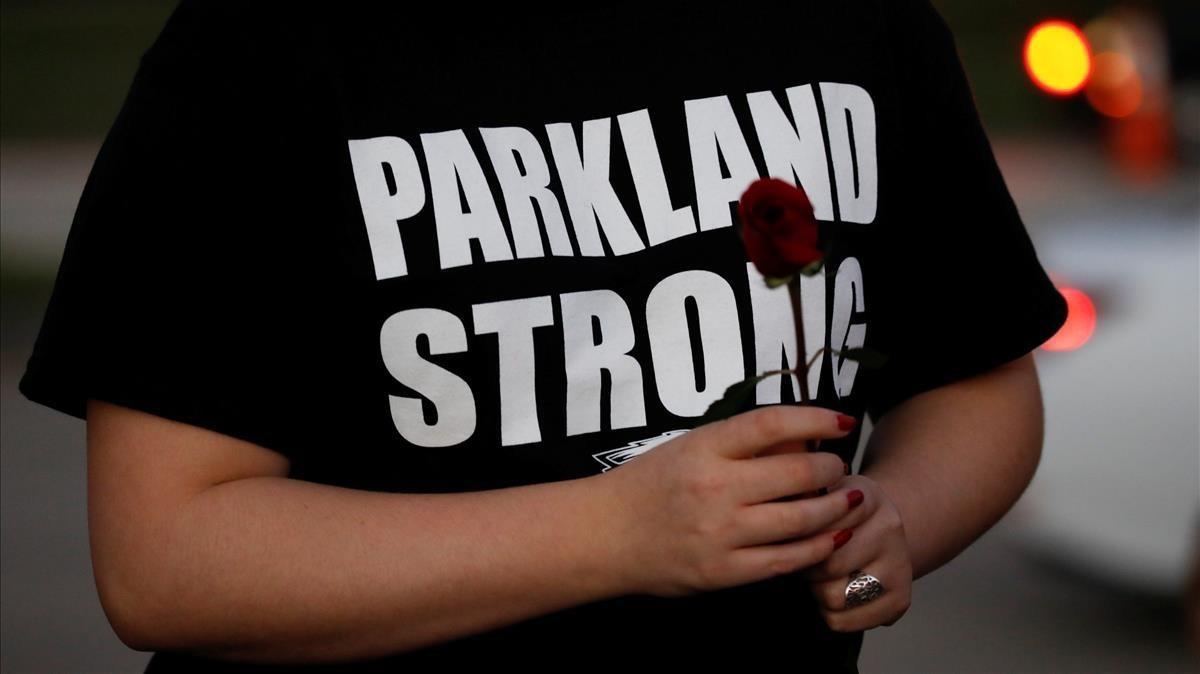 Un asistente a los actos de conmemoración de las víctimas del tiroteo de Parkland con una rosa y el mensaje Parkland fuerte en su camiseta