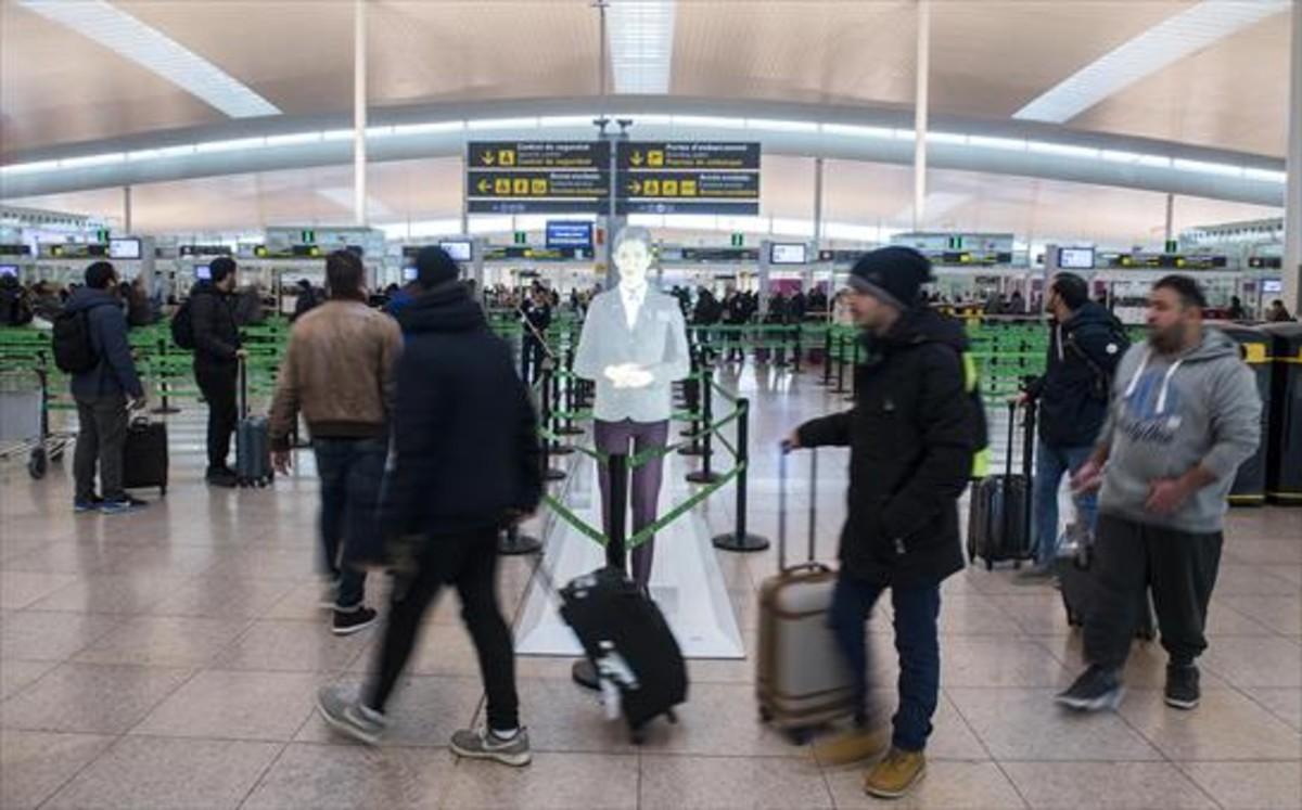 Varios pasajeros se dirigen al control de seguridad antes de embarcar, ayer, en la T-1 del aeropuerto de El Prat.
