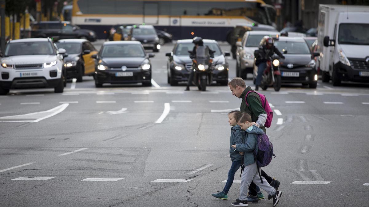 Un padre agarra a sus hijos para cruzar la calle de Aragó, probablemente, la más peligrosa de Barcelona