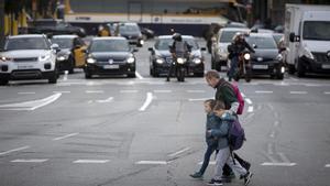 Un padre agarra a sus hijos para cruzar la calle de Aragó lo más pronto posible