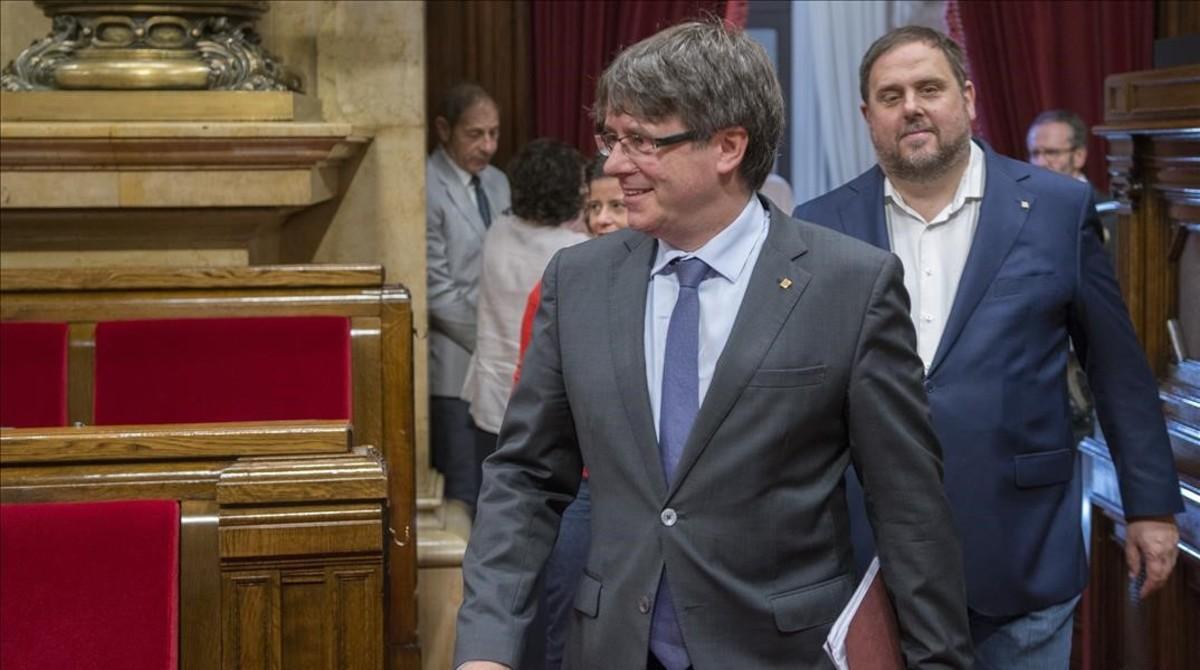 El presidente de la Generalitat, Carles Puigdemont, y el vicepresidente del Govern, Oriol Junqueras, en el hemiciclo del Parlament.