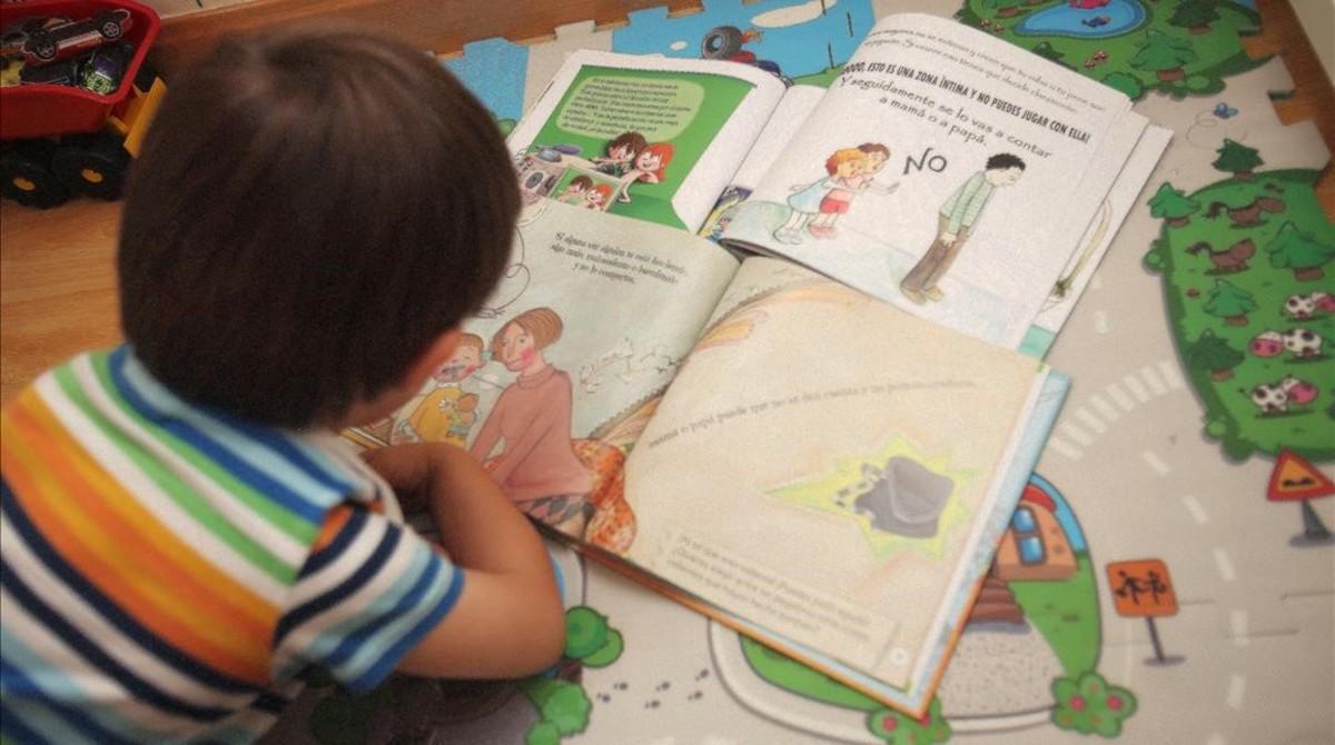 Un niño de tres años mira las viñetas de varios cuentos infantiles.