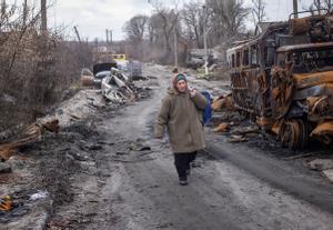 Una mujer camina frente a vehículos destrozados en la localidad ucraniana de Torske, situada en la región oriental de Donetsk.
