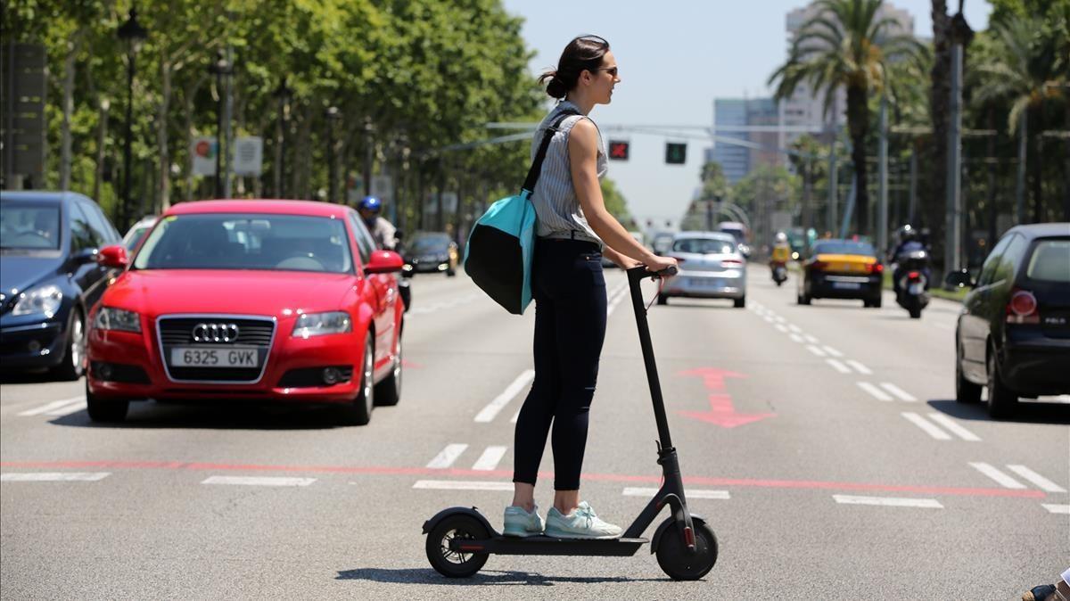 Una mujer circula por Barcelona en patinete eléctrico, este verano.