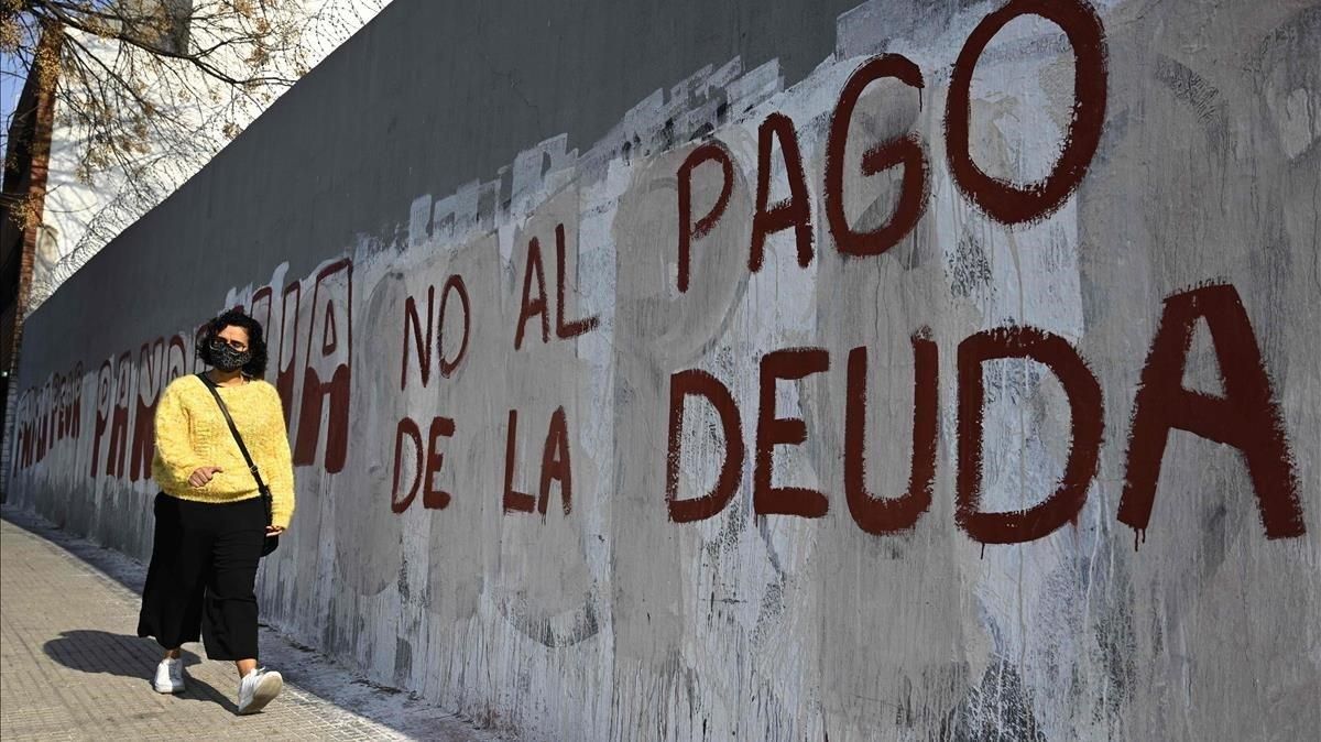 Una mujer camina junto a una pintada que insta a no pagar la deuda, el lunes en Buenos Aires. Una mujer camina junto a una pintada que insta a no pagar la deuda, el lunes en Buenos Aires.