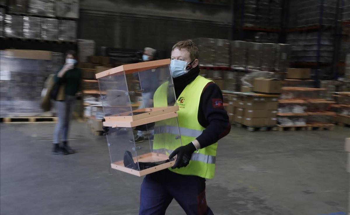 Urnas, papeletas y equipos de protección, preparados para el 14 F. En la foto, un trabajador traslada unas urnas en los talleres municipales, en Barcelona.