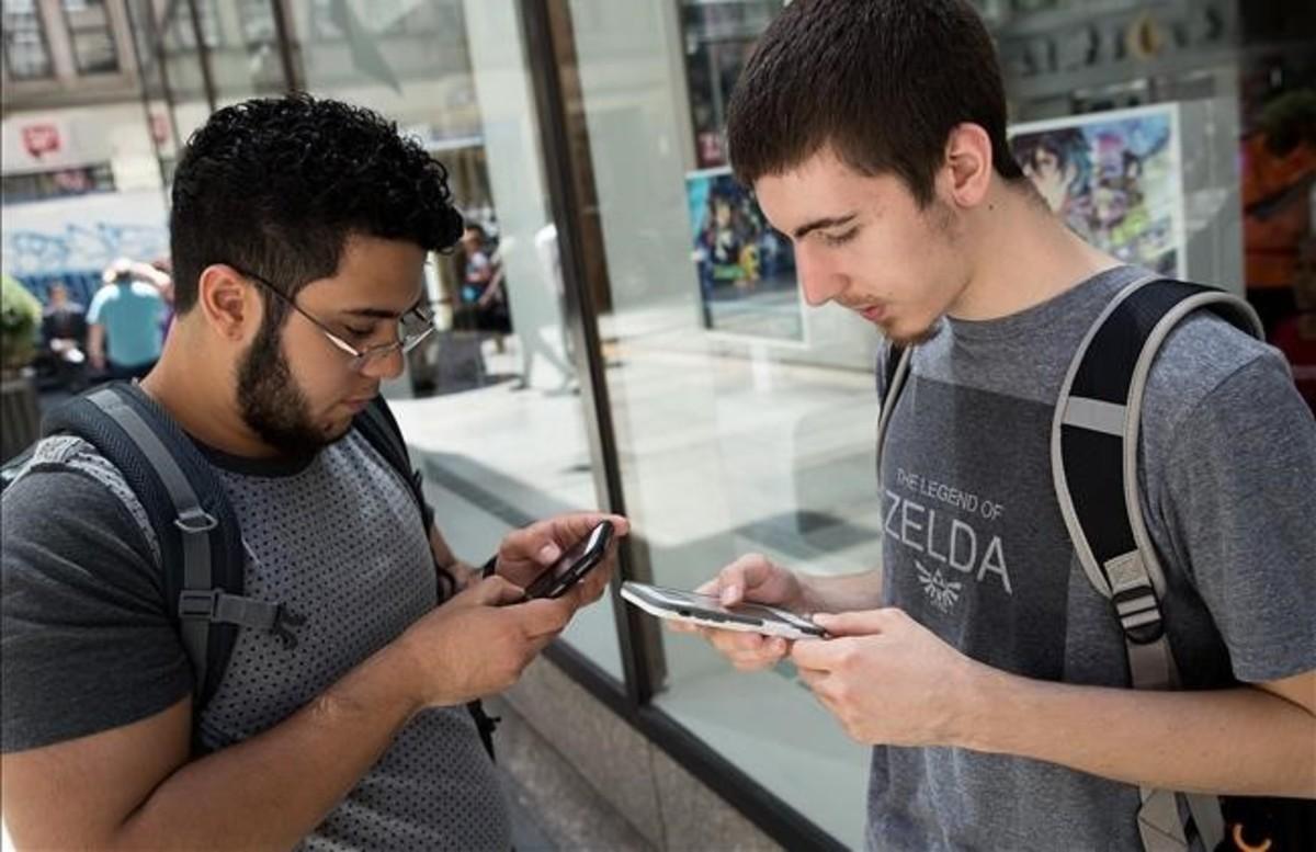 Dos jóvenes usando la nueva aplicación para móviles Pokémon Go.