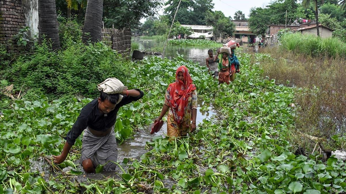 Los residentes de la aldea de Jaynagar en el distrito de Sitamarhi en el estado indio de Bihar, llevan sus pertenencias entre las aguas de las inundaciones después de las fuertes lluvias monzónicas en julio de 2019