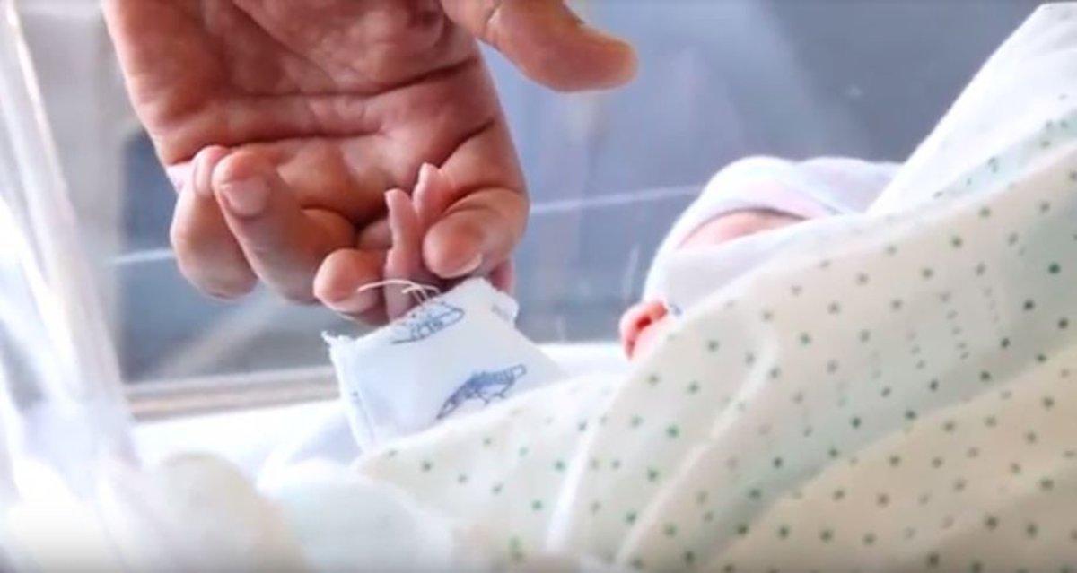 Un bebé recién nacido coge la mano de uno de sus padres.
