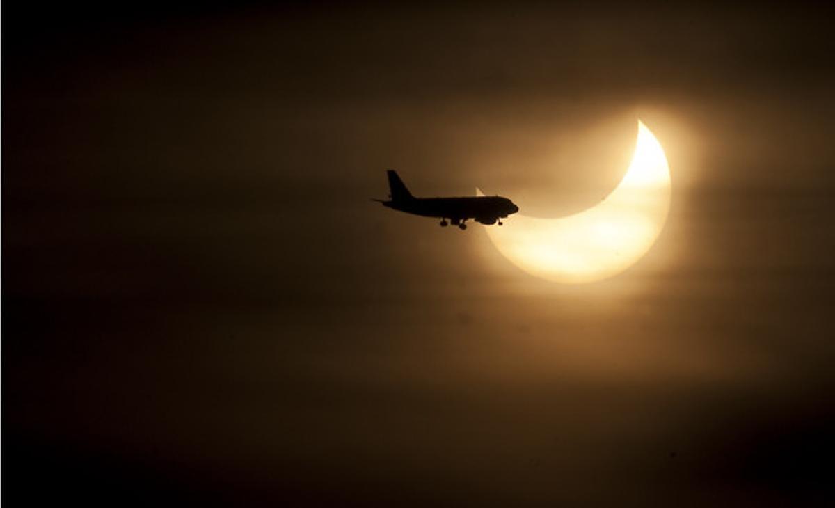 Un avión cruza el Sol eclipsado parcialmente por la Luna.