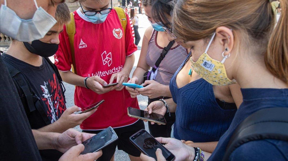 Grupo de jovenes mirando juntos sus telefonos moviles