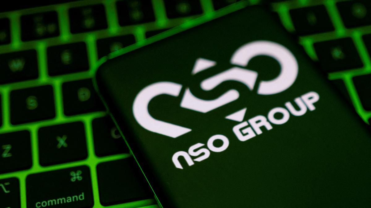 El logotipo de NSO Group en un teléfono inteligente colocado ante un teclado de ordenador 