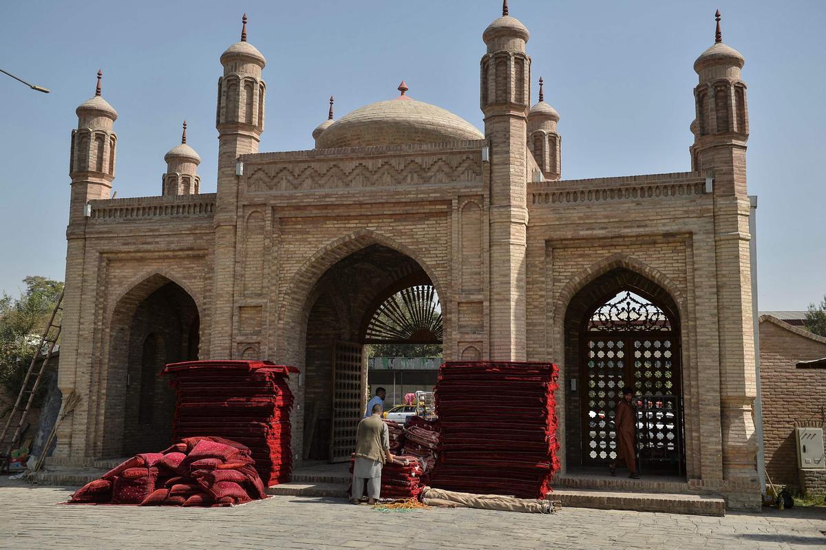 Varios trabajadores colocan almohadas y cojines a la entrada de la mequita de Eid Gah para los rezos por las víctimas en el atentado del domingo.