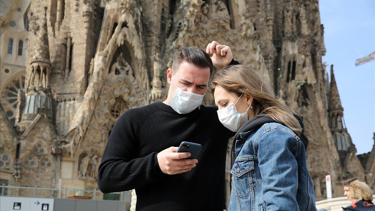 Dos turistas con mascarilla frente el templo de la Sagrada Família, a mediados de marzo, antes del confinamiento.