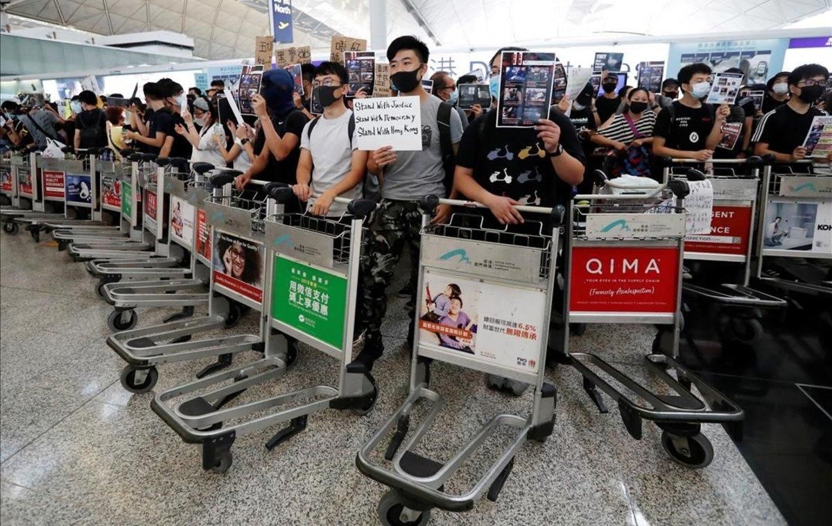Manifestantes usan carritos para hacer barricadas frente a las puertas de acceso en el aeropuerto de Hong Kong. Manifestantes usan carritos para hacer barricadas frente a las puertas de acceso en el aeropuerto de Hong Kong.
