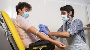 Un investigador de la Universidad de Oxford toma muestras de sangre de un voluntario para el ensayo de vacuna contra el coronavirus.