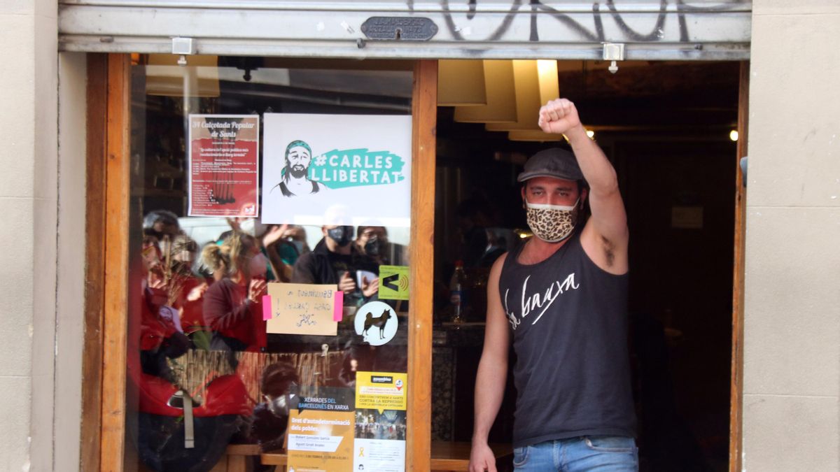 Carles, en la entrada de su taberna, saluda a los manifestantes, en Sants Carles, en la entrada de su taberna, saluda a los manifestantes, en Sants