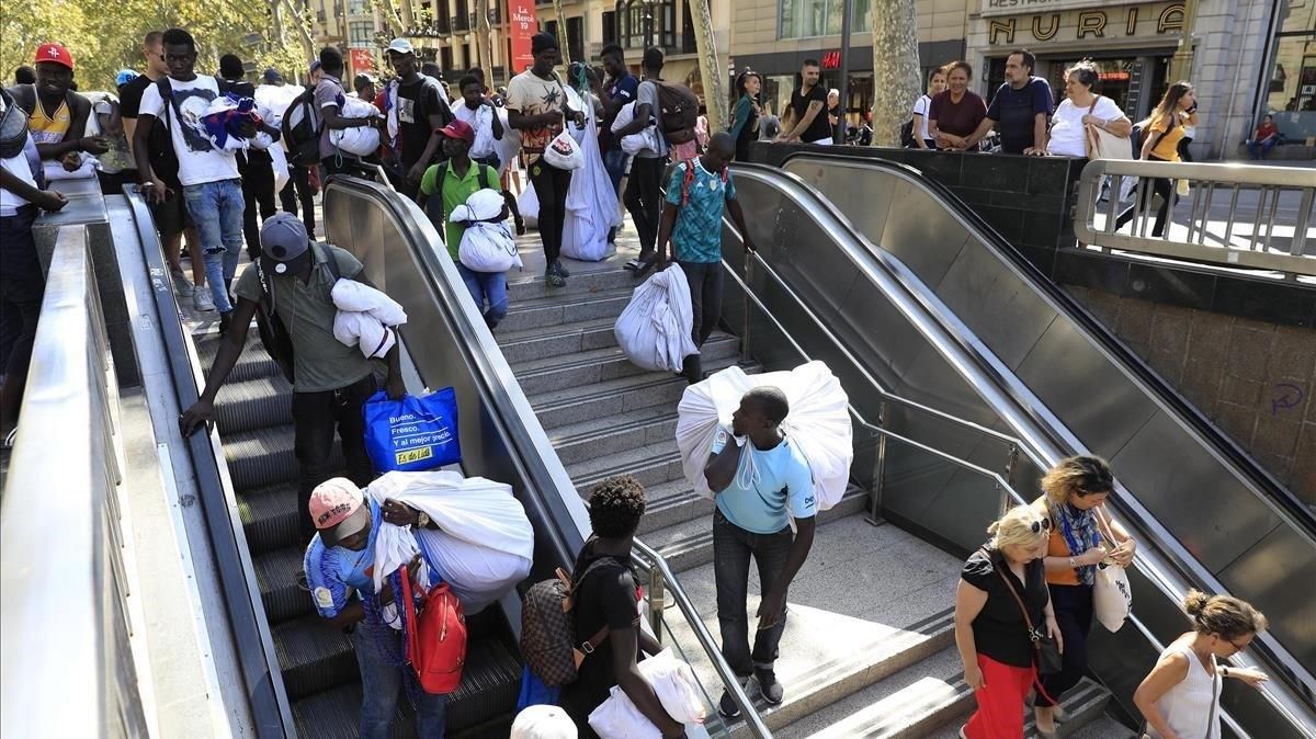 Un grupo de manteros entra en el metro huyendo de la presión policial en la Rambla, este jueves. Un grupo de manteros entra en el metro huyendo de la presión policial en la Rambla, este jueves.