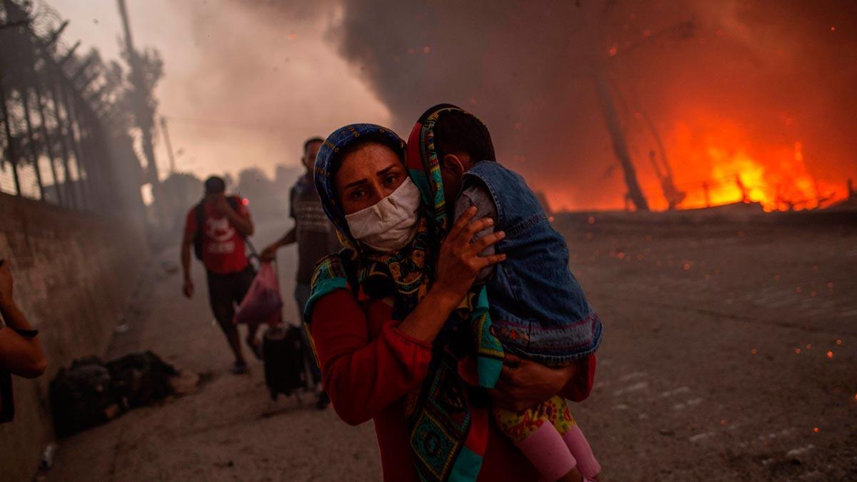 Una mujer huye con su hijo del incendio declarado en el campo de refugiados de Moria, el 9 de septiembre del 2020.