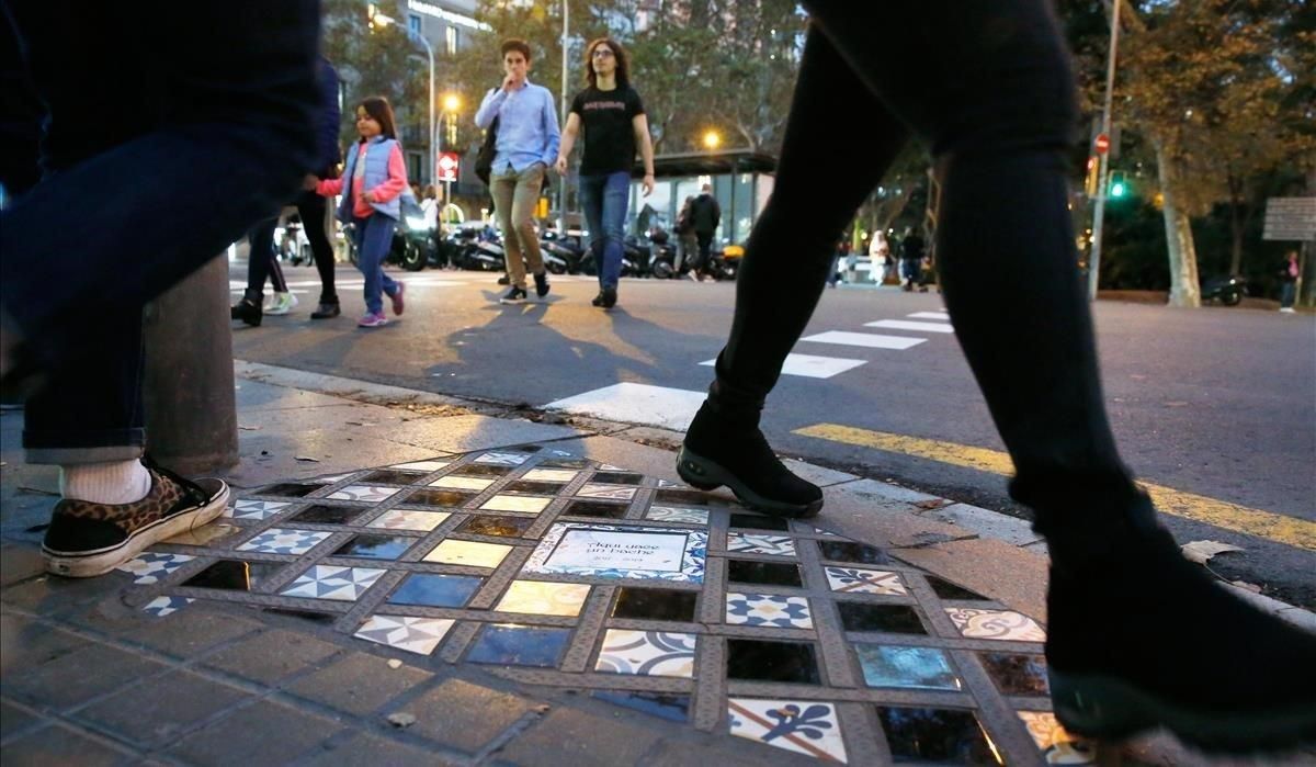 Peatones pasan junto a la obra de Ememem en la plaza de Urquinaona. Peatones pasan junto a la obra de Ememem en la plaza de Urquinaona.
