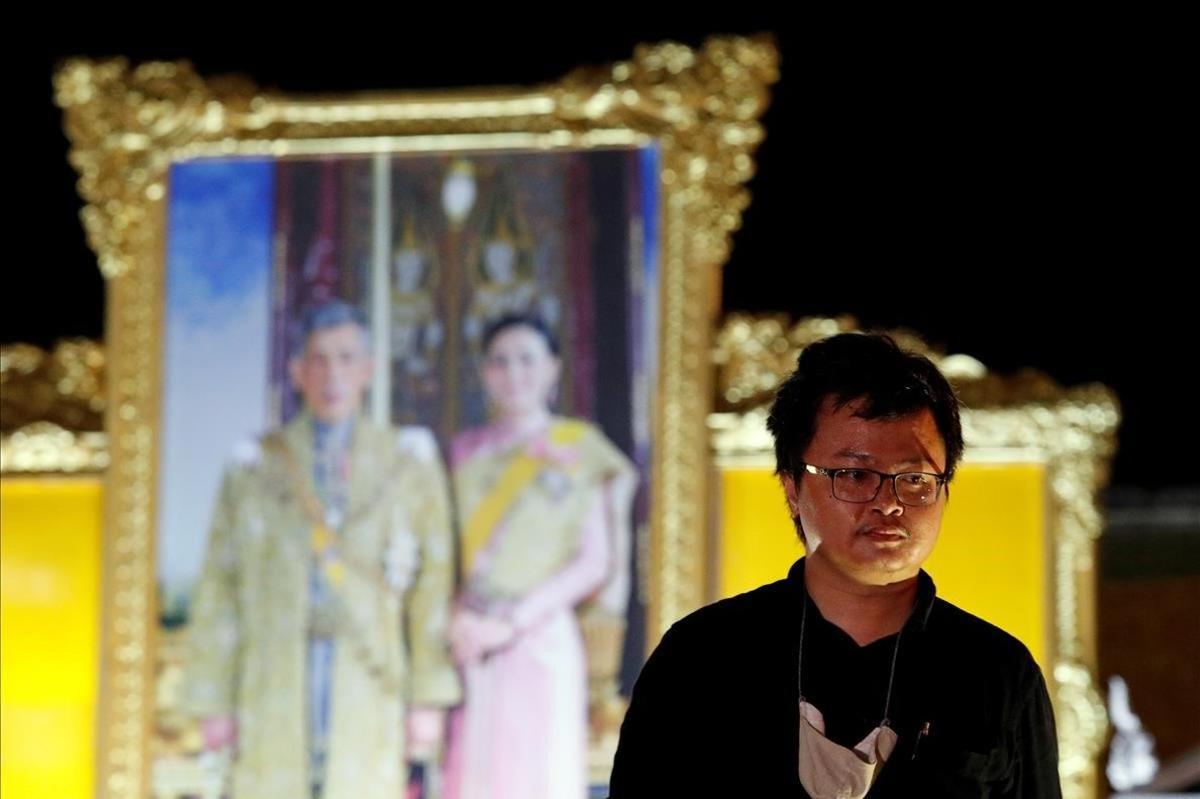 Anon Nampa, uno de los líderes de las protestas antigubernamentales, posa ante una foto de los reyes de Tailandia.