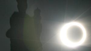 Imagen del sol durante un eclipse en la fase de anularidad en Santiago de Compostela, junto a una estatua de la catedral.