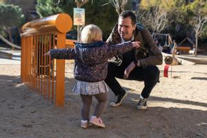 Un hombre juega con su hija en un parque de Barcelona.
