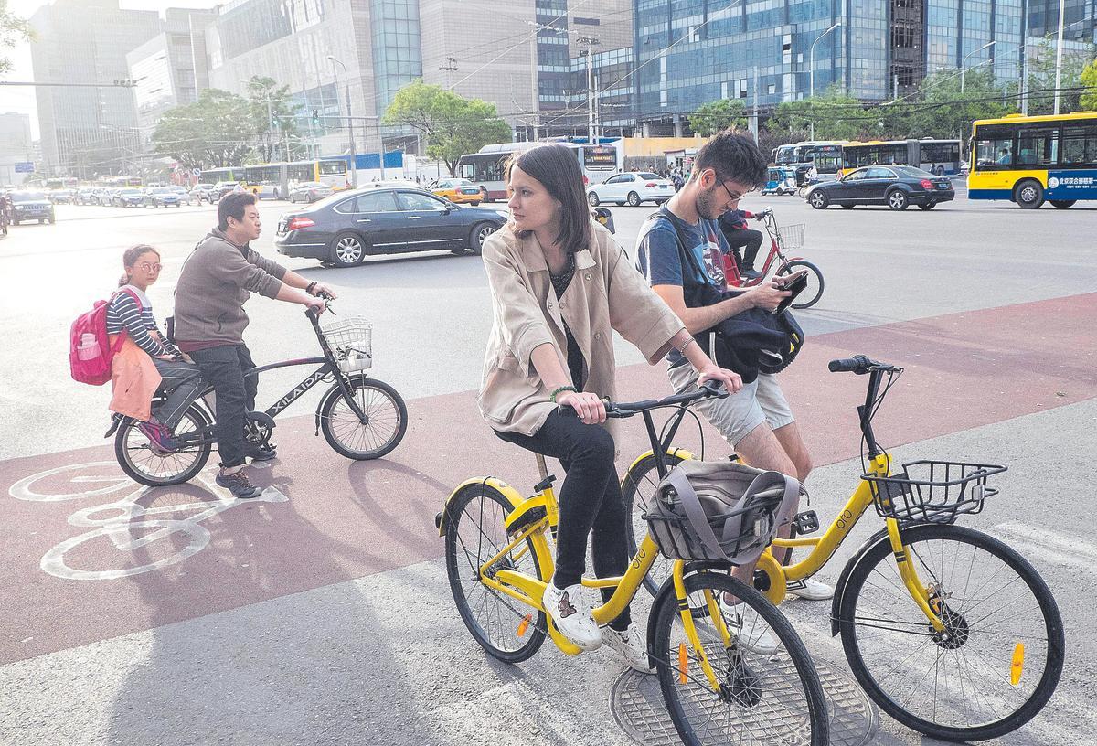 Turistas occidentales en biciCleta por la capital de China, Pekín. 