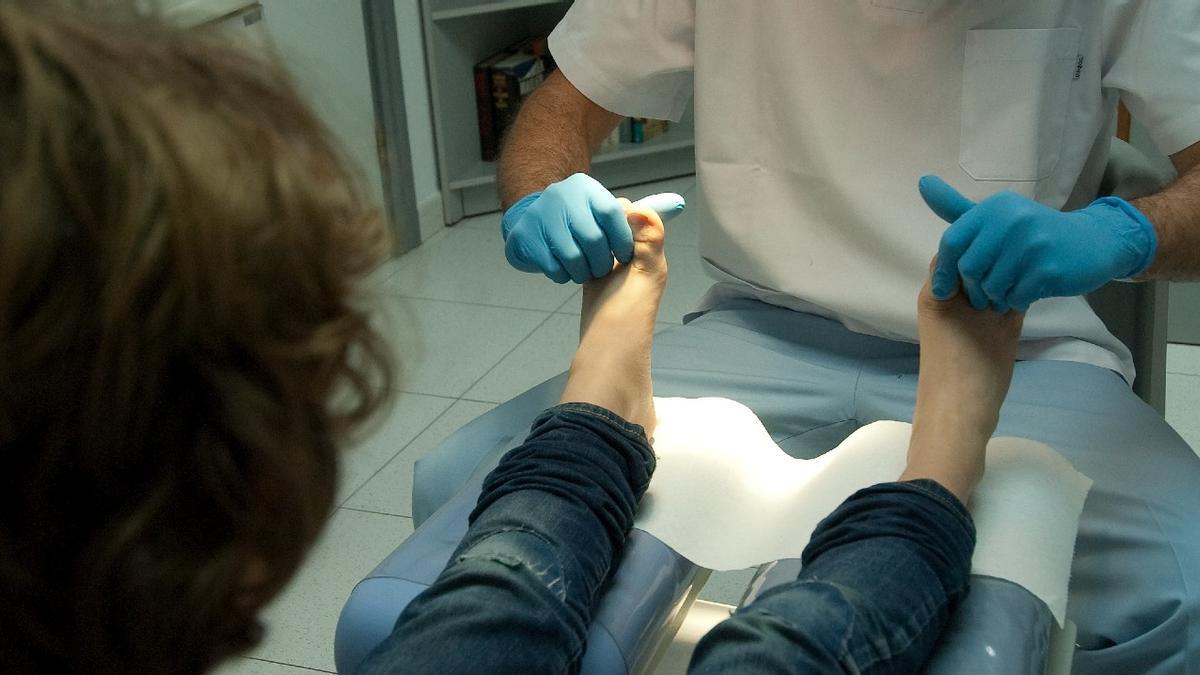 Un hombre manipula los pies de una mujer en la consulta.