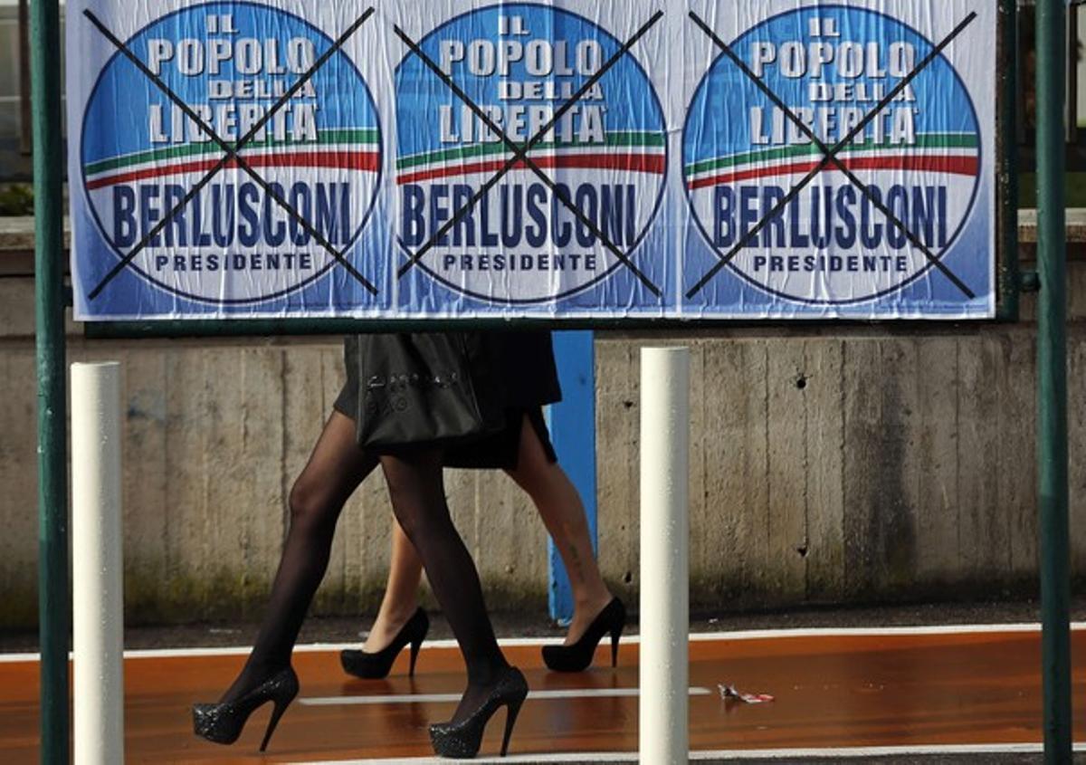 Dos mujeres pasan junto a unos carteles electorales de Berlusconi en Nápoles.