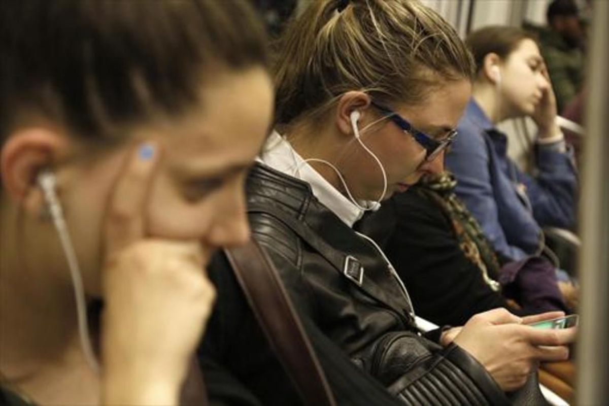 Jóvenes escuchando música con auriculares en el metro. Jóvenes escuchando música con auriculares en el metro.