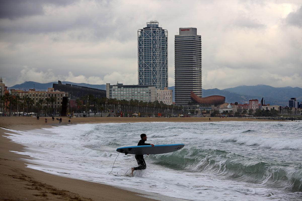 Un surfista entra en el mar a la altura de la Barceloneta, en Barcelona.