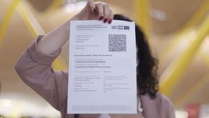 Una mujer muestra su certificado covid.