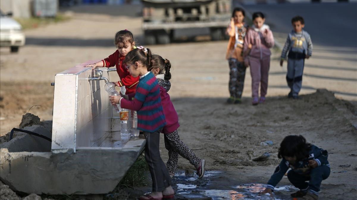 Niños palestinos llenan botellas de agua en una fuente en el campo de refugiados de Khan Yunis, al sur de Gaza, el pasado día 11.