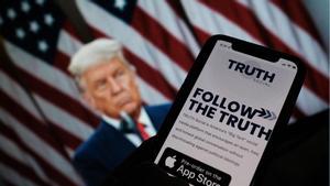 Fotoilustración en la que una persona busca en su teléfono la red Truth Social. Al fondo, una foto de Donald Trump.