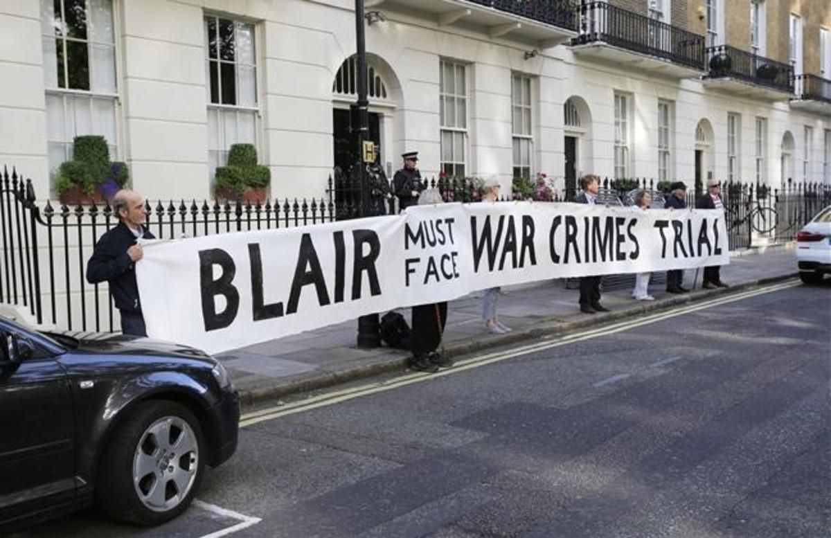 Manifestantes frente a la casa de Tony Blair con la pancarta Blair debe hacer frente a un juicio por crímenes de guerra. Manifestantes frente a la casa de Tony Blair con la pancarta Blair debe hacer frente a un juicio por crímenes de guerra.