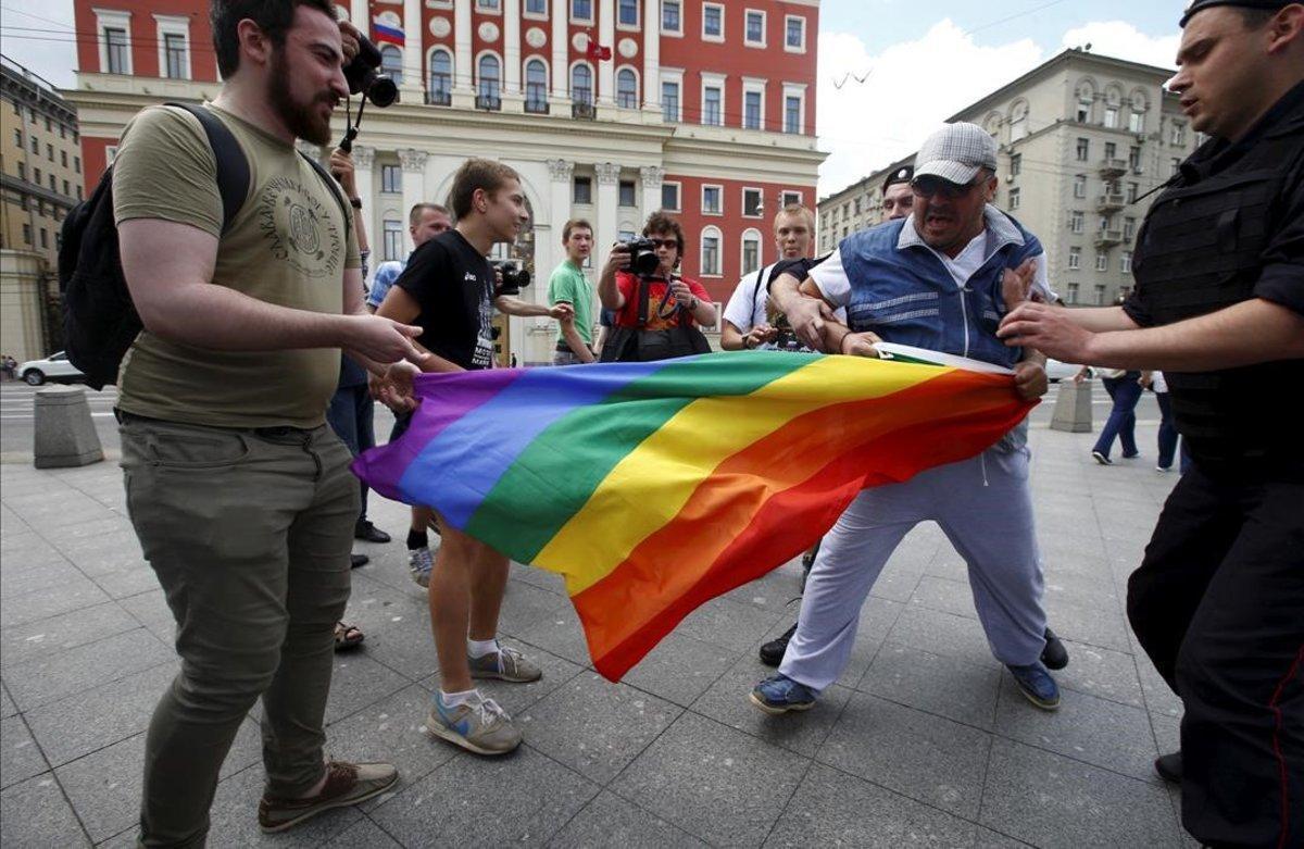 Manifestantes homófobos tratan de romper una bandera gay de un grupo de homosexuales en Moscú.