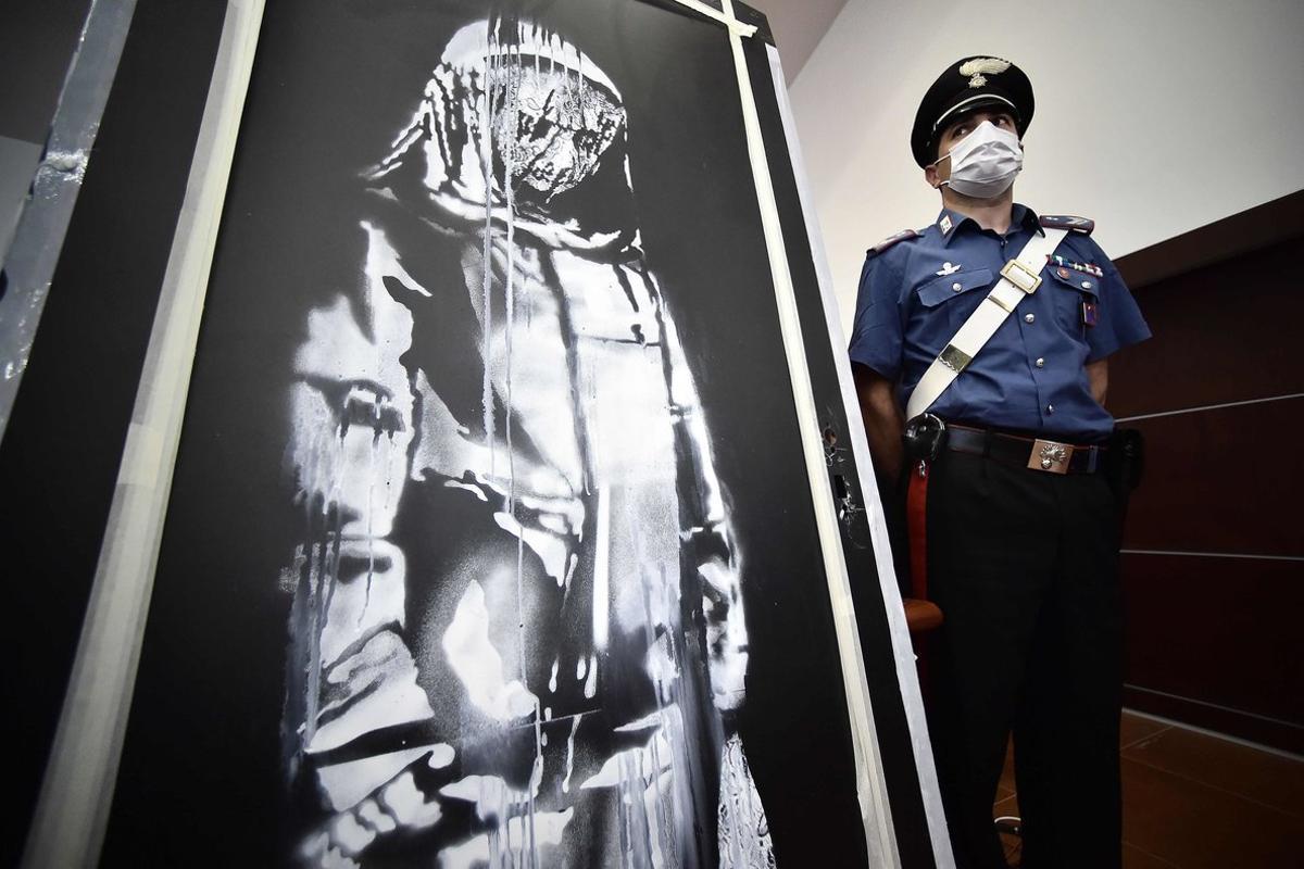 Un policía junto al cuadro de Banksy recuperado en Italia.