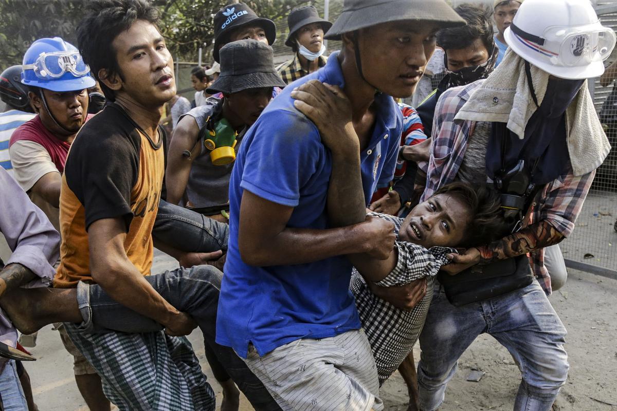 Varios hombres trasladan a un herido en las protestas contra el golpe militar, este domingo en Yangón.