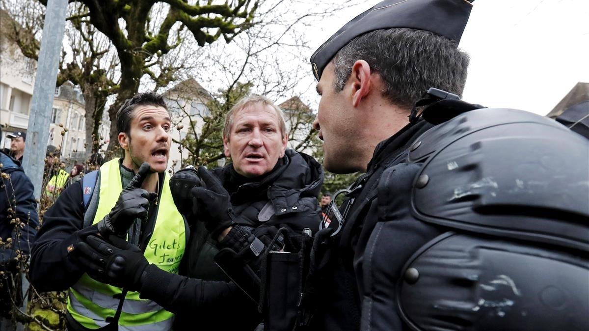 Varios  chalecos amarillos  forcejean con gendarmes galos mientras aguardan la llegada del presidente frances  Emmanuel Macron  a un debate con alcaldes de una zona rural del sur este viernes en Souillac.