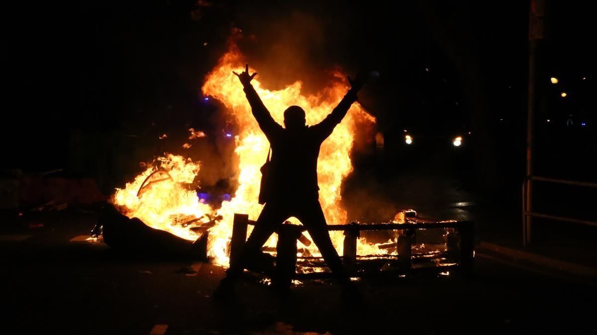 Un manifestante en el centro de Barcelona, frente a un contenedor ardiendo, el miércoles. Un manifestante en el centro de Barcelona, frente a un contenedor ardiendo, el miércoles.