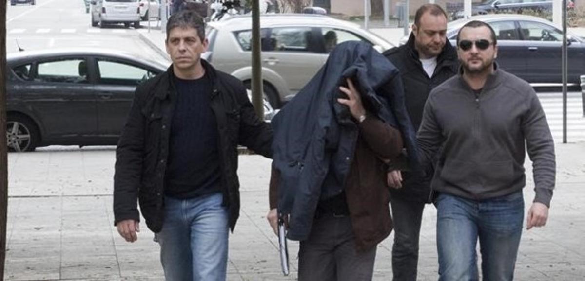 Joaquim Benítez, con la cabeza cubierta, se dirige al juzgado para prestar declaración, rodeado de agentes de los Mossos d’Esquadra.